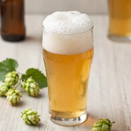 a high quality wide shot of a tasty glass of beer, with a dense foam, there is hops on the table, blur background