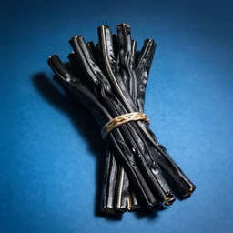 a bundle of black twizzlers on a blue background, licorice candy, looks like flat rope