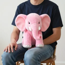 Photo of a man on a chair with his pink miniature elephant on his lap