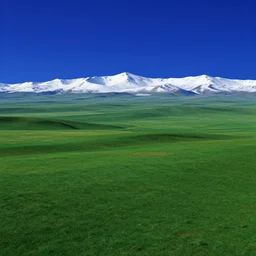 a surreal landscape where the sky is a deep, rich blue and the land is a mix of different shades of green. in the distance, there are mountains that are covered in a blanket of snow. vray