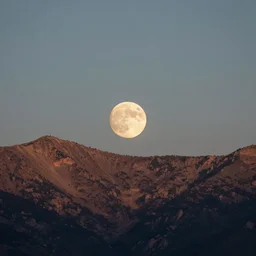 the moon setting behind mountains