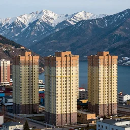 abandoned urban housing project, high rise apartment complex, multi colored buildings, on a high mountain landscape, lakes and snowy mountains