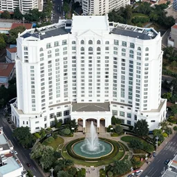 a white grand hotel, with a hundred of windows, and a fountain at the yard of the hotel, satellite view photo