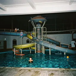an eerie photo of an abandoned indoor water park from the 1 9 9 0 s at night, disposable film