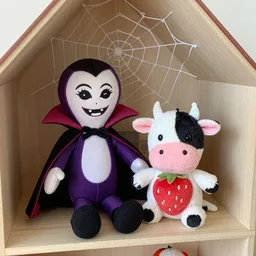 an easy to make Halloween themed vintage vampire squid doll accompanied by an adorable strawberry cow plush, the two are friends and are seated by a dollhouse in a cobweb filled attic