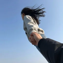 a person holding hands with a friend while flying high in the sky, windy