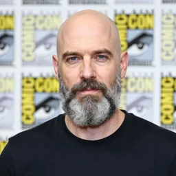 ethan van sciver with a bald head grey beard and pointed nose, posing for pictures at comic con