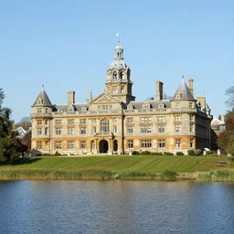 photograph of a grand victorian college building in the countryside by a large lake. detailed architecture, realistic, well lit and blue sky.