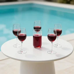 5 5 mm photo of best glass of redwineglass with juice on a zen minimalist round white table with gorgeous pool in the background. highly detailed 8 k. intricate. lifelike. soft light,
