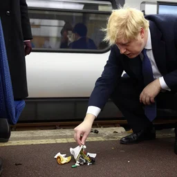 boris johnson littering on a train, throwing garbage on the ground