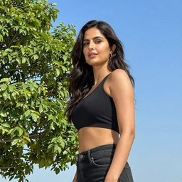katrina kaif under a beautiful blue sky standing besides a green tree